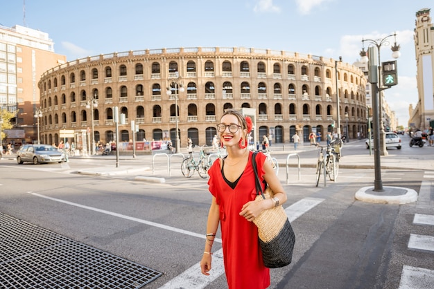 Junge Frau im roten Kleid zu Fuß die Straße in der Nähe der Stierkampfarena Amphitheater in der Stadt Valencia, Spanien