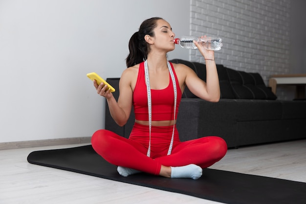 Junge Frau im roten Trainingsanzug, der Übung oder Yoga zu Hause tut