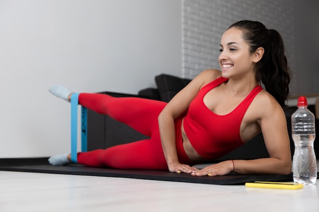 Junge Frau im roten Trainingsanzug, der Übung oder Yoga zu Hause tut