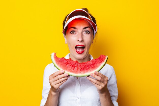 Junge Frau im roten Visier, die eine Scheibe Wassermelone hält