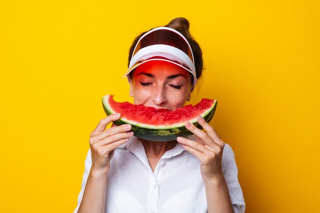 Junge Frau im roten Visier, die eine Scheibe Wassermelone hält