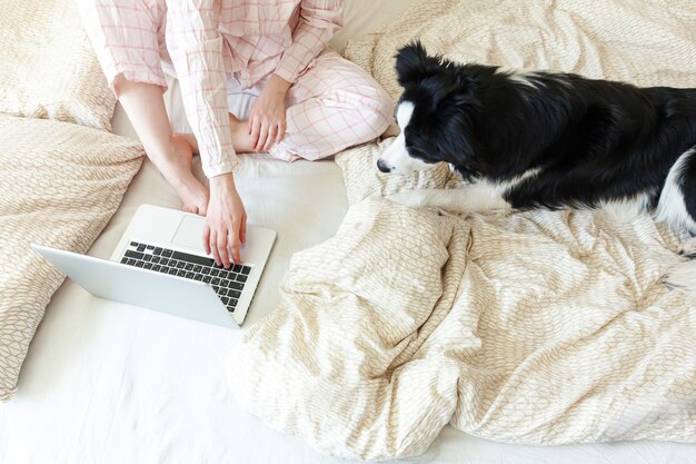 Junge Frau im Schlafanzug, der auf Bett mit Hund sitzt