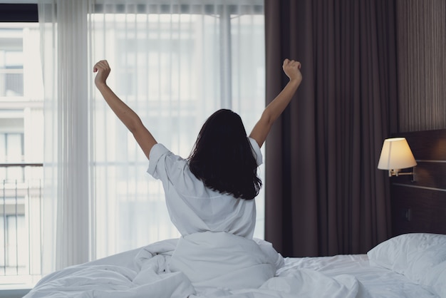 Junge Frau im Schlafzimmer morgens. Mädchen sitzt auf dem Bett