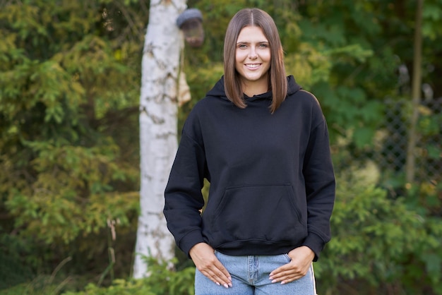 Junge Frau im schwarzen Hoodie. Foto in hoher Qualität