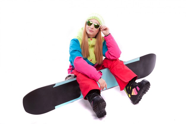 junge frau im ski-outfit und sonnenbrille halten snowboard