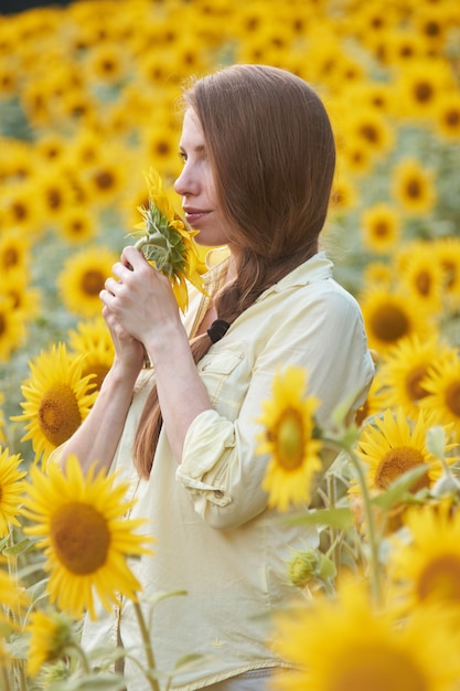 Junge Frau im Sonnenblumenfeld hat Spaß