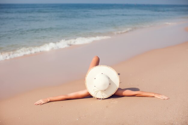 Junge Frau im Sonnenhut und im Bikini am Strand