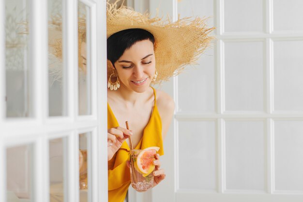 Junge Frau im Strohhut mit einem Cocktail. Sommerferienkonzept