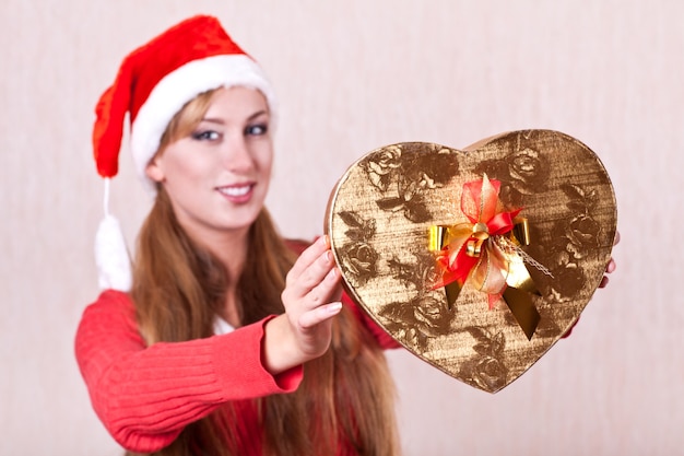 Junge Frau im Weihnachtsmannhut mit Geschenkbox