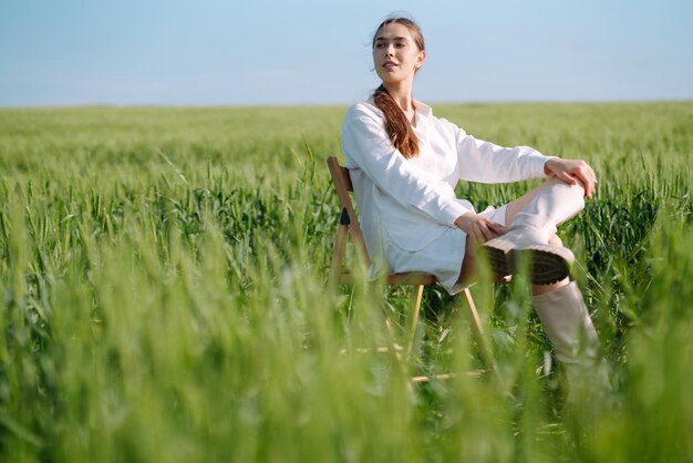 Junge Frau im weißen Anzug posiert im grünen Weizenfeld Mode- und Lifestyle-Konzept