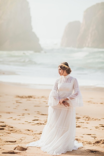 junge Frau im weißen Kleid am Strand spazieren