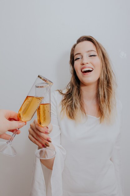 Junge Frau im weißen Kleid, das mit Glas Sekt in den Händen röstet