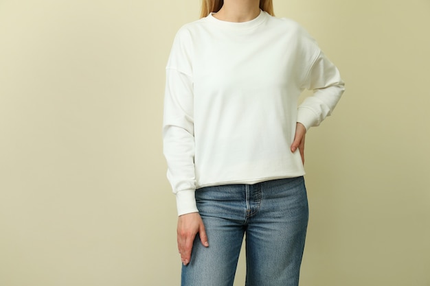 Junge Frau im weißen Sweatshirt gegen beige Oberfläche