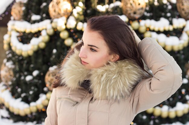 Junge Frau im Winterpark nahe Weihnachtsbaum im Freien