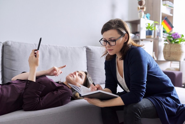 Foto junge frau in absprache mit psychologin. patientin liegt auf der couch und spricht über psychische probleme, traumata. professionelle unterstützung, unterstützung durch psychologen, psychiater, therapeuten