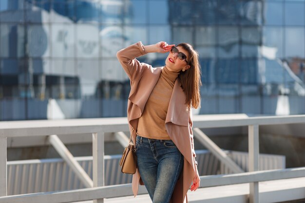 Junge Frau in beigem Mantel und Jeans