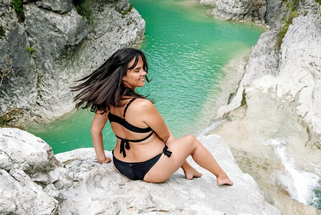 Foto junge frau in bikini sitzt auf einem felsen am fluss wasserfall bikini im freien schönes mädchen