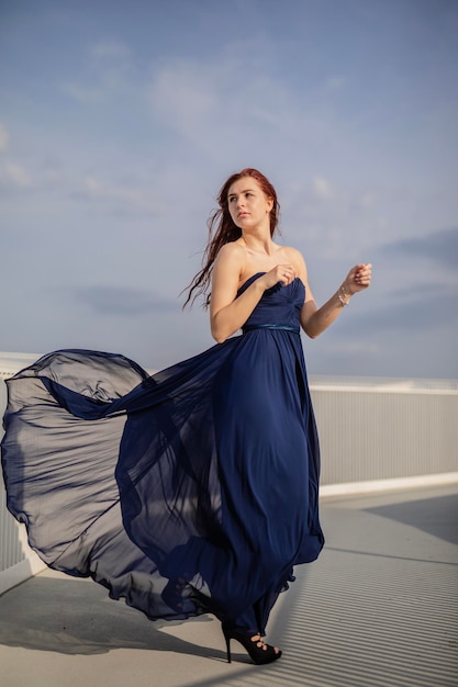 Foto junge frau in blauem kleid steht auf der terrasse des gebäudes