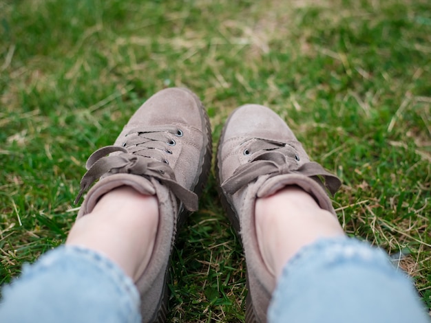 Junge Frau, in Blue Jeans und Turnschuhen sitzend, auf dem grünen Gras sitzend, nah oben