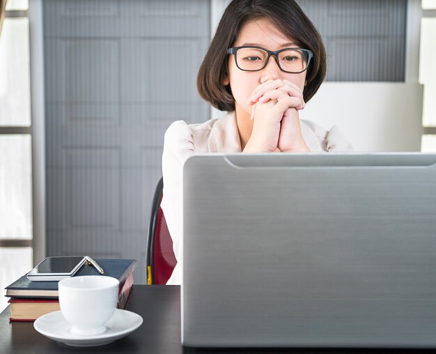 Junge Frau in der intelligenten Freizeitkleidung, die an Laptop arbeitet