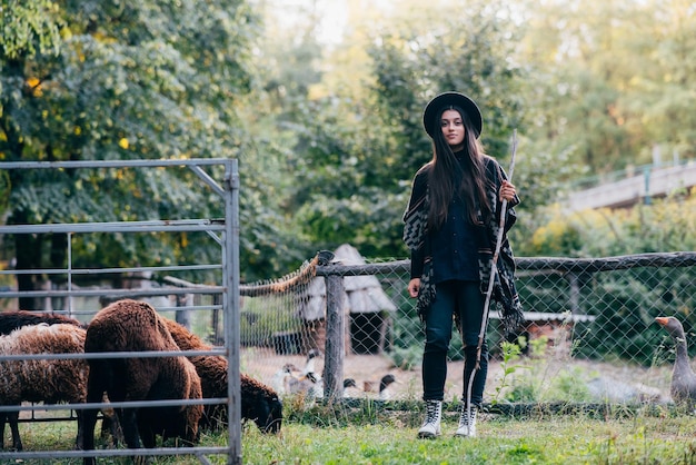 Junge Frau in der Nähe eines Geheges mit Schafen auf einem Bauernhof