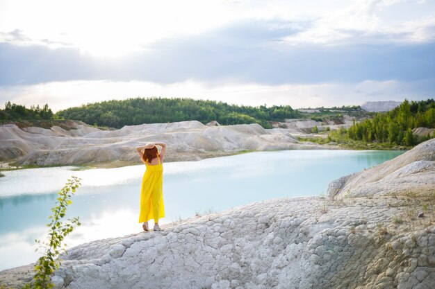 Junge Frau in der Nähe eines Sees mit azurblauem Wasser und steinigen Bergen mit grünen Bäumen. Schöne Aussicht auf den See im Wald