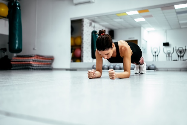 Junge Frau in der Sportkleidung, die Planke an der Turnhalle tut.