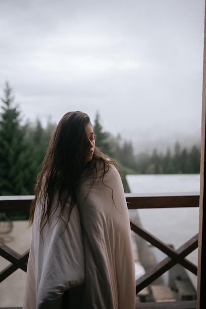 Foto junge frau in eine decke gehüllt auf dem balkon