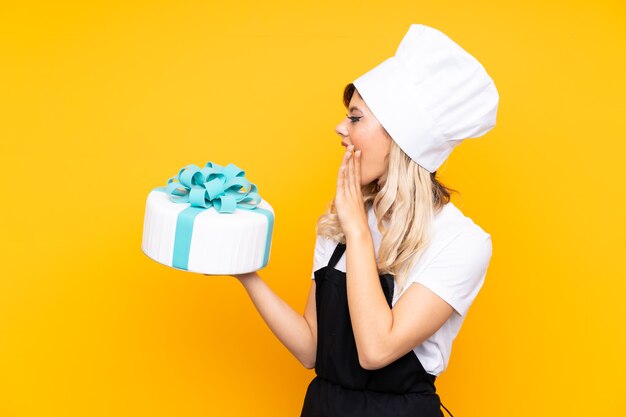 junge Frau in einem Bäckeranzug, hält eine roung Kuchenschachtel