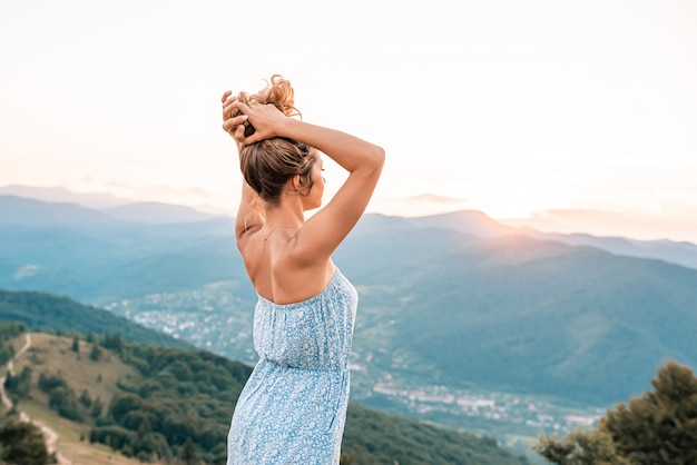Junge Frau in einem blauen Kleid, das auf dem Berg geht