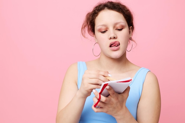 Junge Frau in einem blauen T-Shirt mit einem roten Notizblock und einem Stift von Emotionen Lifestyle unverändert