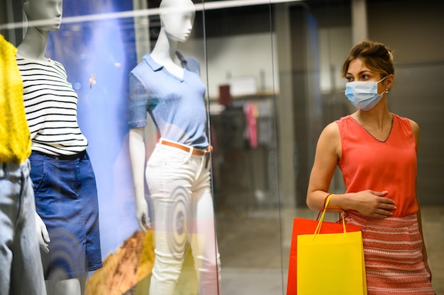 Junge Frau in einem Einkaufszentrum, die eine Schutzmaske gegen die Covid-19-Coronavirus-Pandemie trägt