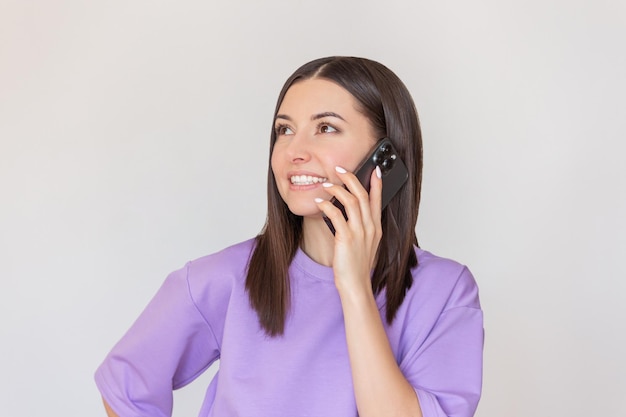 Junge Frau in einem lila T-Shirt telefoniert und lächelt. Mobile Kommunikation