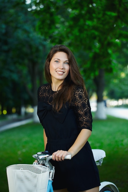 junge Frau in einem Park, der mit einem Retro-Fahrrad aufwirft