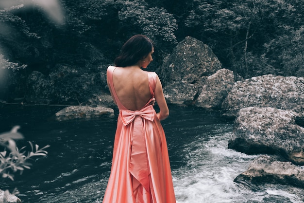 Junge Frau in einem rosa Kleid posiert