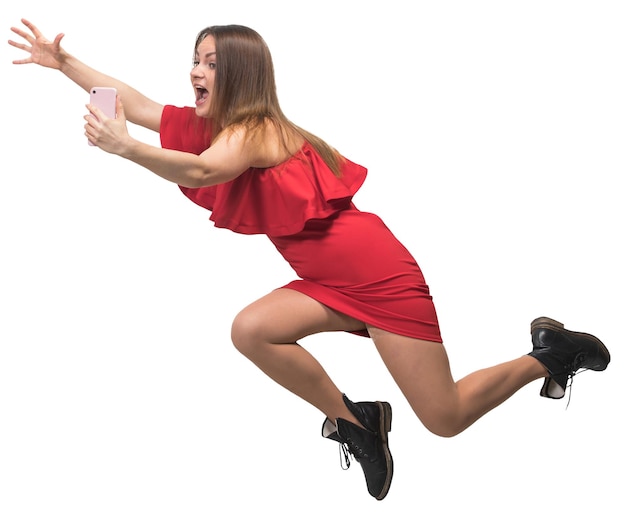 Junge Frau in einem roten Kleid läuft, hält ein Smartphone in der Hand