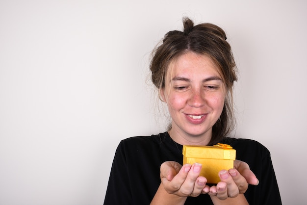 junge Frau in einem schwarzen T-Shirt freut sich, Geschenk anzunehmen. Geschenkkonzept annehmen