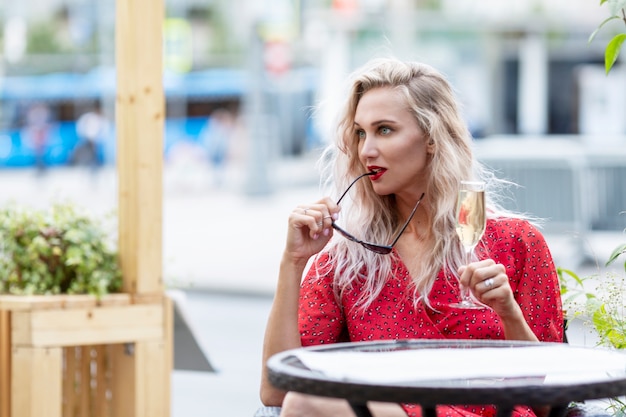 Junge Frau in einem Straßencafé mit einem Glas Champagner in ihren Händen