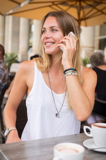 Junge Frau in einem Straßencafé schaut sich am Handy um