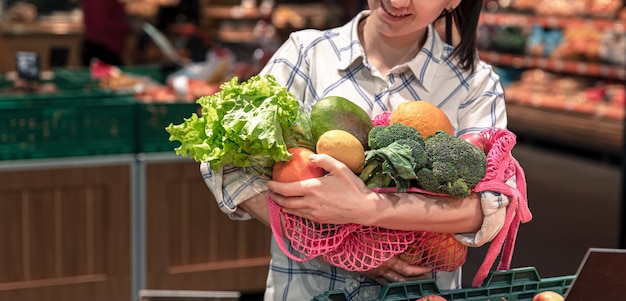 Junge Frau in einem Supermarkt mit Gemüse und Obst, die Lebensmittel kauft