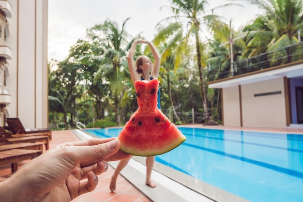 Junge Frau in einem Wassermelonenkleid auf einem Poolhintergrund. Das Konzept von Sommer, Ernährung und gesunder Ernährung