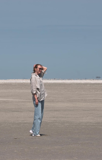 Junge Frau in einem weißen Hemd steht am Strand