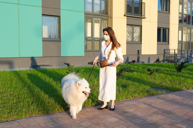 Junge Frau in einem weißen Kleid, das ihren Hund geht