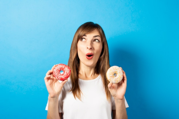 Junge Frau in einem weißen T-Shirt hält Donuts isoliert