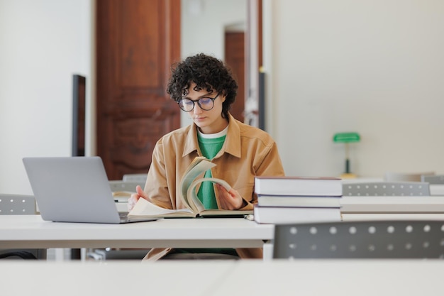 Junge Frau in einer Bibliothek oder Coworking arbeitet an einem Laptop Online-Bildung und arbeitet an einem kreativen Projekt oder Diplom