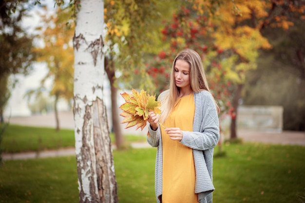 Junge Frau in einer grauen Strickjacke im Herbstpark