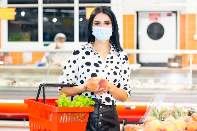 Junge Frau in einer medizinischen Einwegmaske kauft im Supermarkt ein