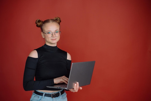 Junge Frau in einer schwarzen Bluse mit Brötchenfrisur steht mit einem Laptop gegen einen Universitätsstudenten