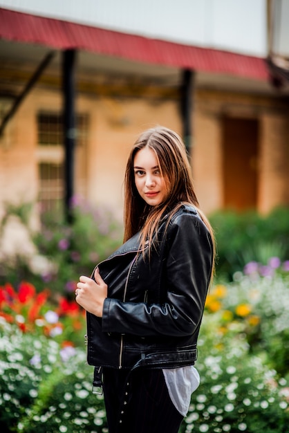 Junge Frau in einer schwarzen Lederjacke im Garten