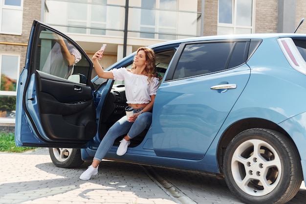 Junge frau in freizeitkleidung mit ihrem elektromobil tagsüber im freien